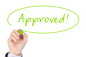 Hand writing the word "approved" for a mortgage refinance