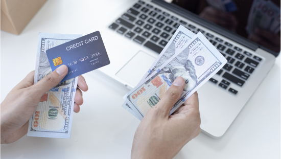 credit card and cash in hand with computer